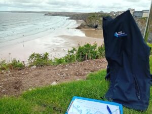 Landslip, landslide and rockfall survey on Towan Beach with jacket and work notes.